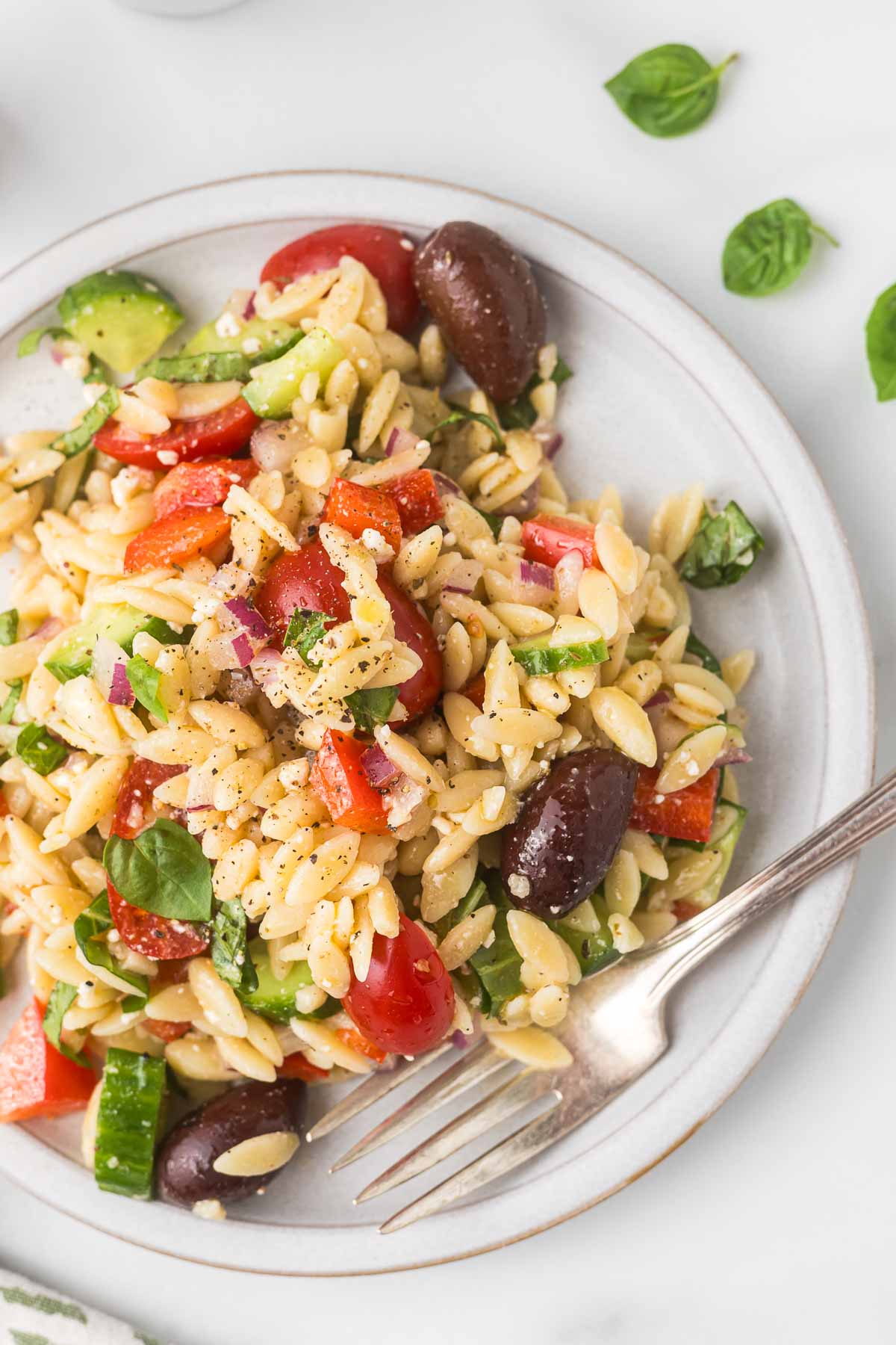 Orzo salad on a plate with a fork.