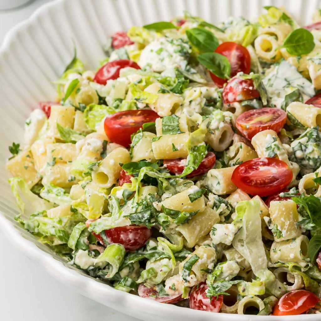 Caesar salad with pasta in a white serving bowl.