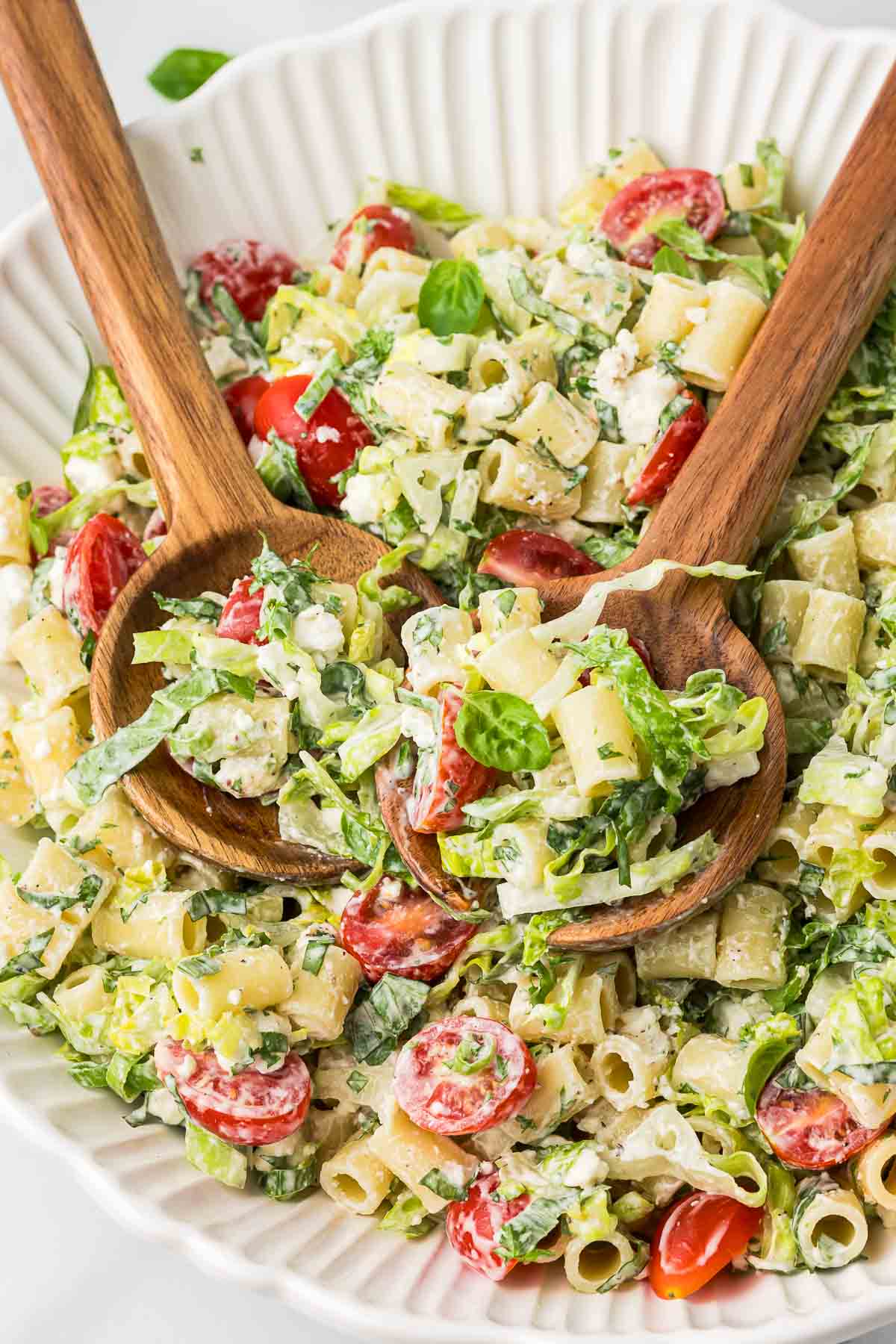 Pasta Caesar Salad in a bowl with wooden serving spoons.
