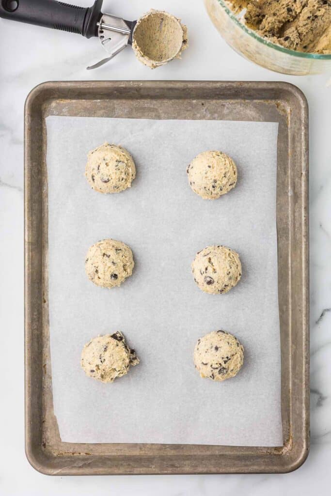 Cookie dough oreo shaped into balls on a cookie sheet.