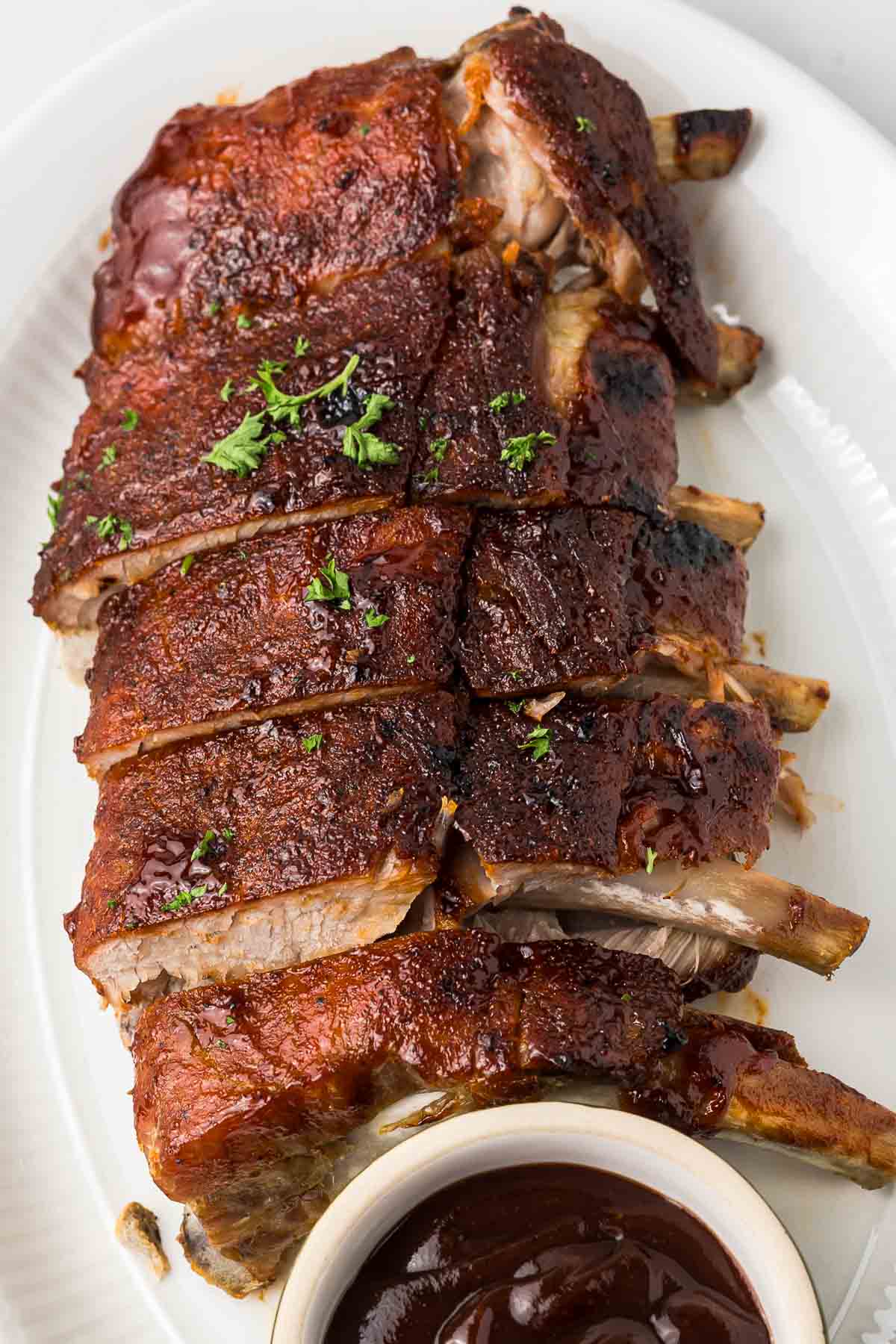 Baby back ribs crock pot recipe on a white plate with bbq sauce.