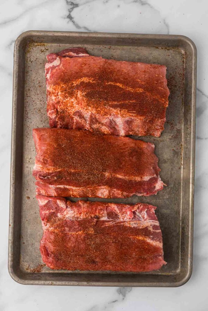 Slow cooker baby back ribs with seasoning before adding to the crock pot.