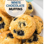 Close-up of delicious blueberry white chocolate muffins on a white plate. Text overlay reads, "Blueberry White Chocolate Muffins" and "Great Grab & Go Treat!" Visit cookingupmemories.com for the full recipe!