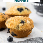 A close-up showcases blueberry white chocolate muffins cooling on a wire rack. Fresh blueberries are scattered around, with a bowl and napkin in the background. The text "Blueberry White Chocolate Muffins" graces the top, celebrating this delightful treat.