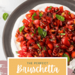 A black dish holds a vibrant bruschetta dip crowned with chopped tomatoes and basil. Beneath, on a beige rectangle, the text reads "The Perfect Bruschetta Dip," accompanied by a recipe website URL.