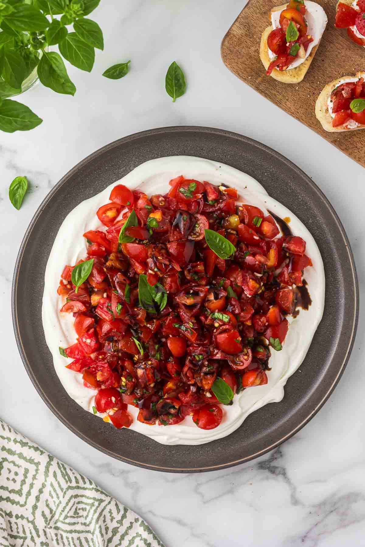 chopped basil, olive oil, and balsamic vinegar to the tomato mixture on top of whipped goat cheese