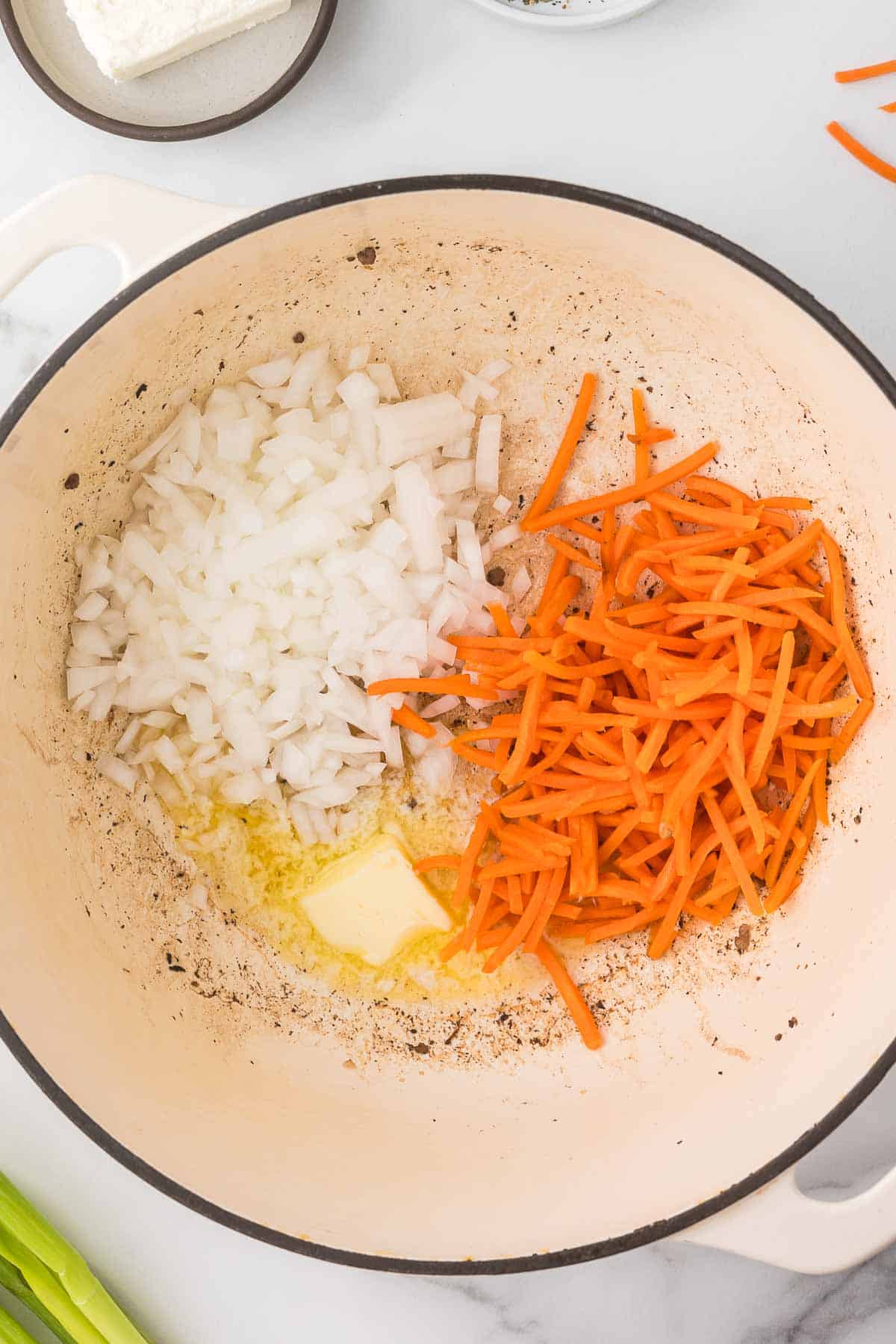 Onions, carrots and butter in a dutch oven to make velveeta cheeseburger soup.