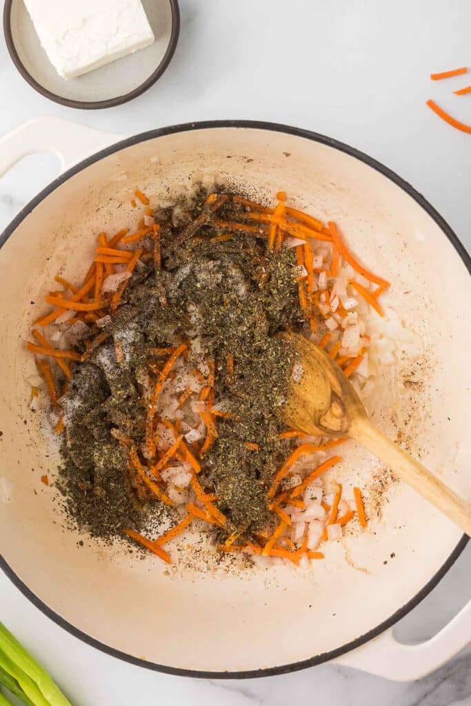 Onions, carrots and spices in a dutch oven. 