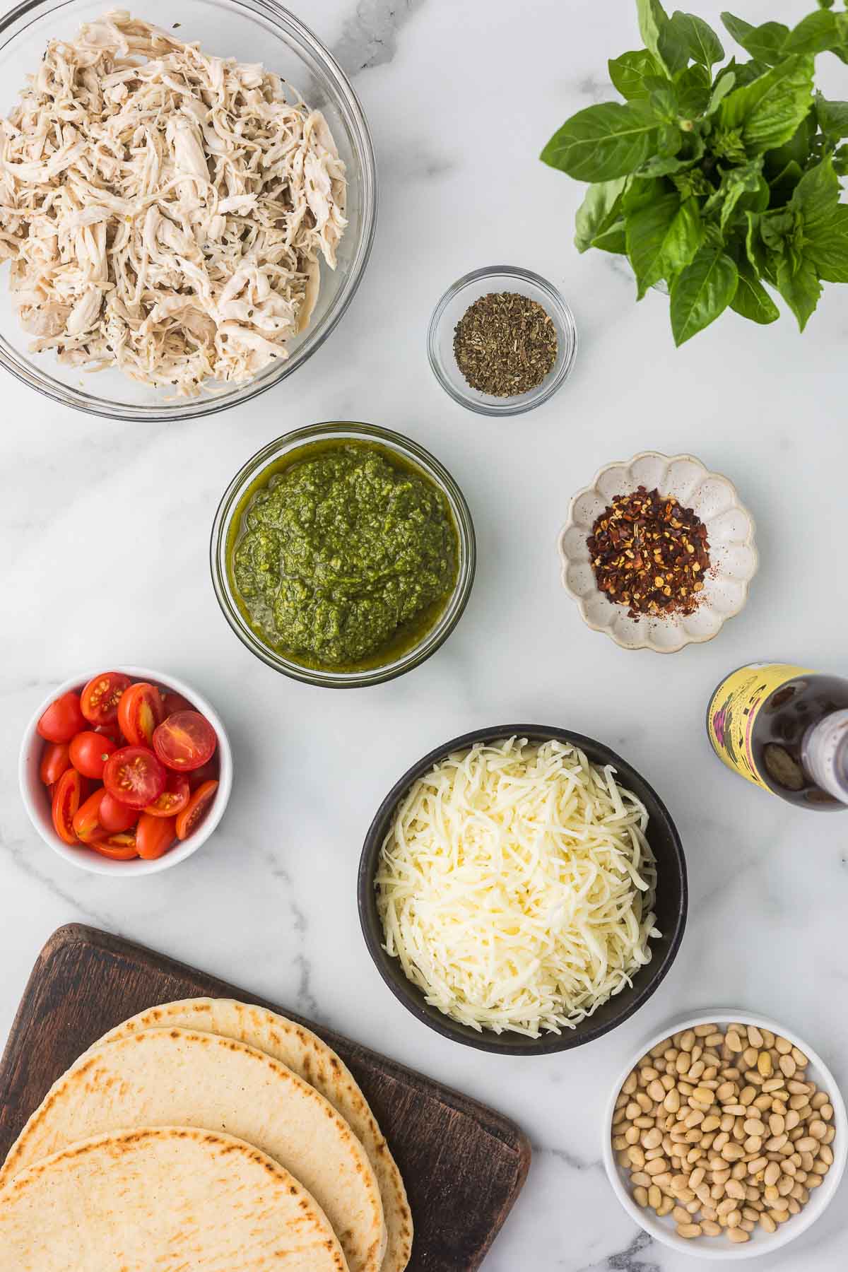 Ingredients to make pesto chicken flatbread.