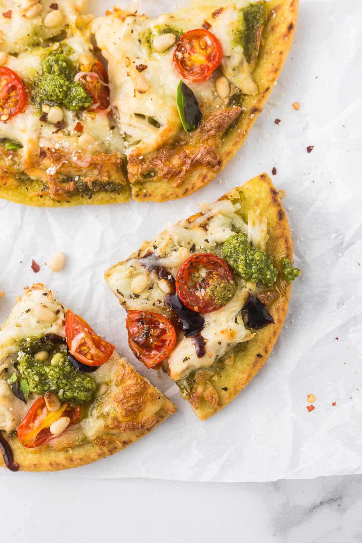 Chicken Pesto Flatbread pizza from the top down photograph of a piece with balsamic glaze and fresh basil.