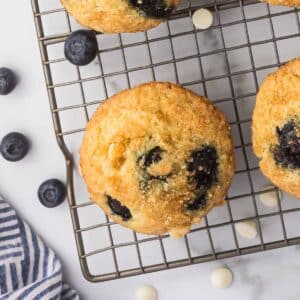 Blueberry white chocolate muffins on a cooling rack.