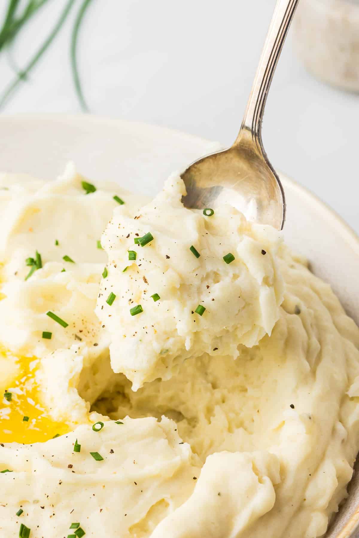 Mashed Potatoes with chives on a spoon.