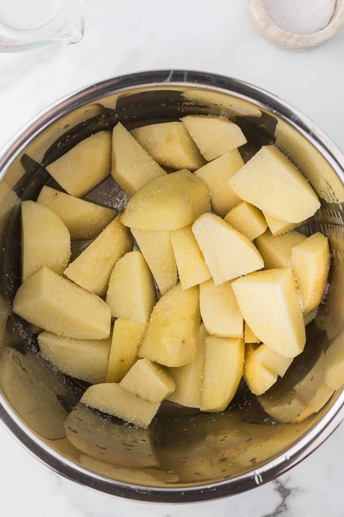 Quartered peeled potatoes in an instant pot with salt and butter.