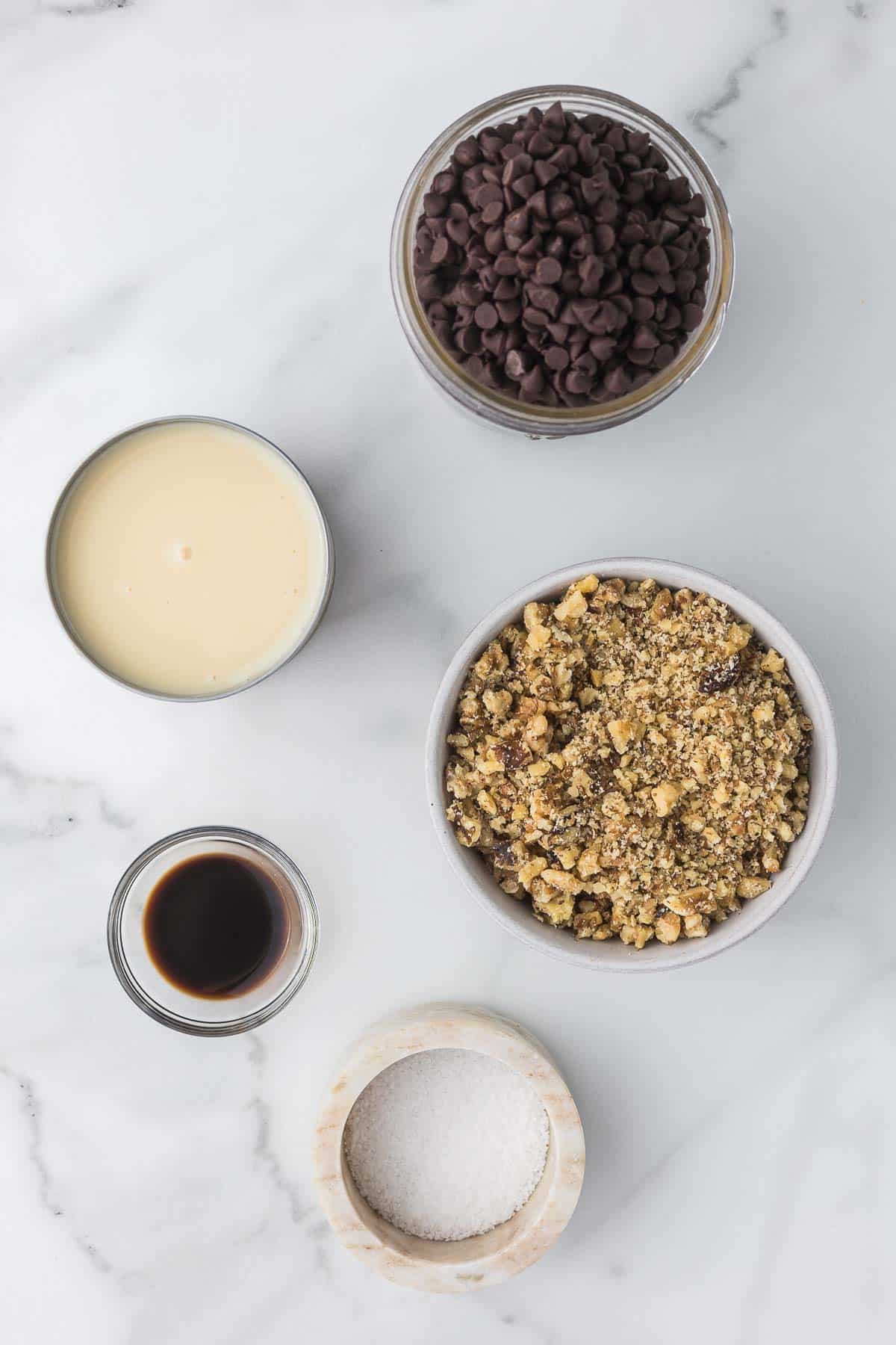 Simple ingredients to make walnut fudge including walnuts, chocolate chips, salt, vanilla and sweetened condensed milk.