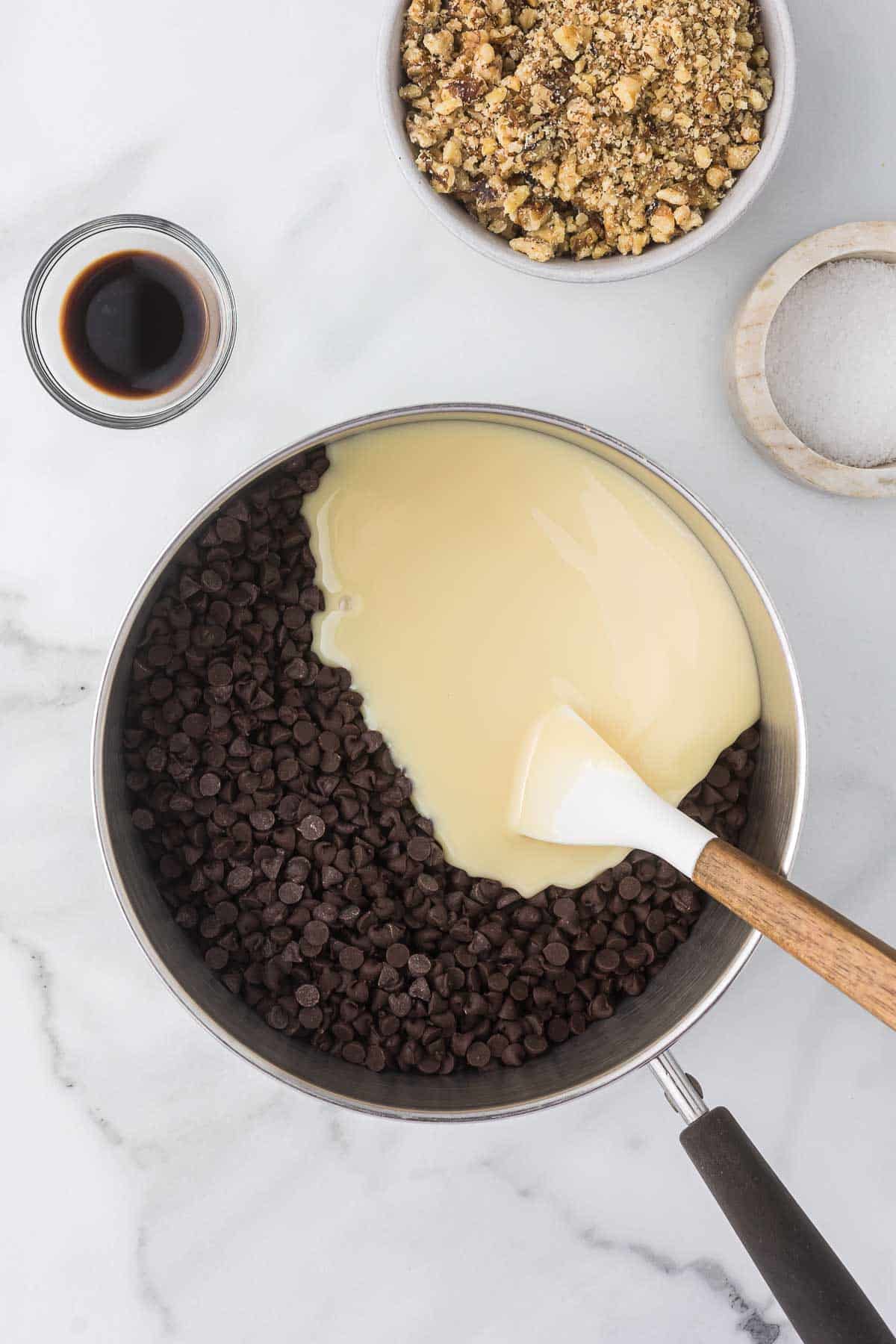 Chocolate chips and sweetened condensed milk in a sauce pan before melting the chips.