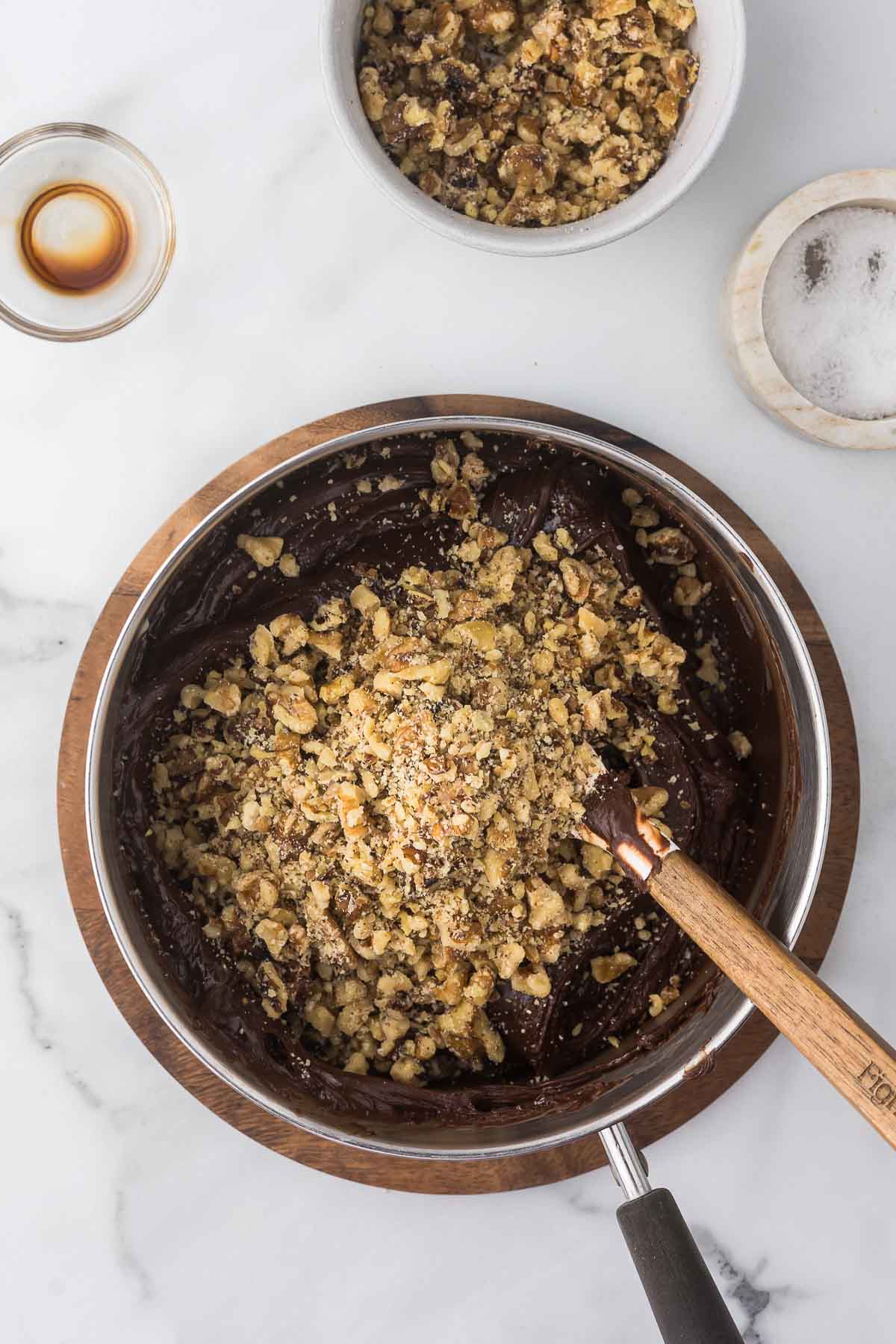 Walnuts being added to a sauce pan with fudge.