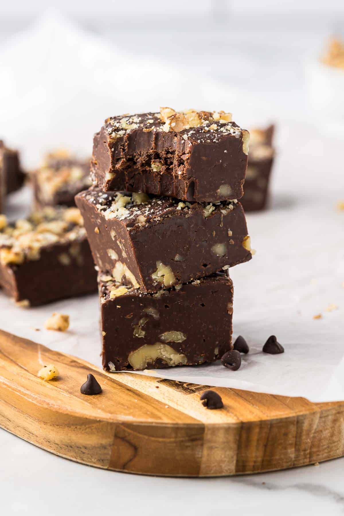 Chocolate Walnut Fudge cut into pieces stacked three high on a cutting board.