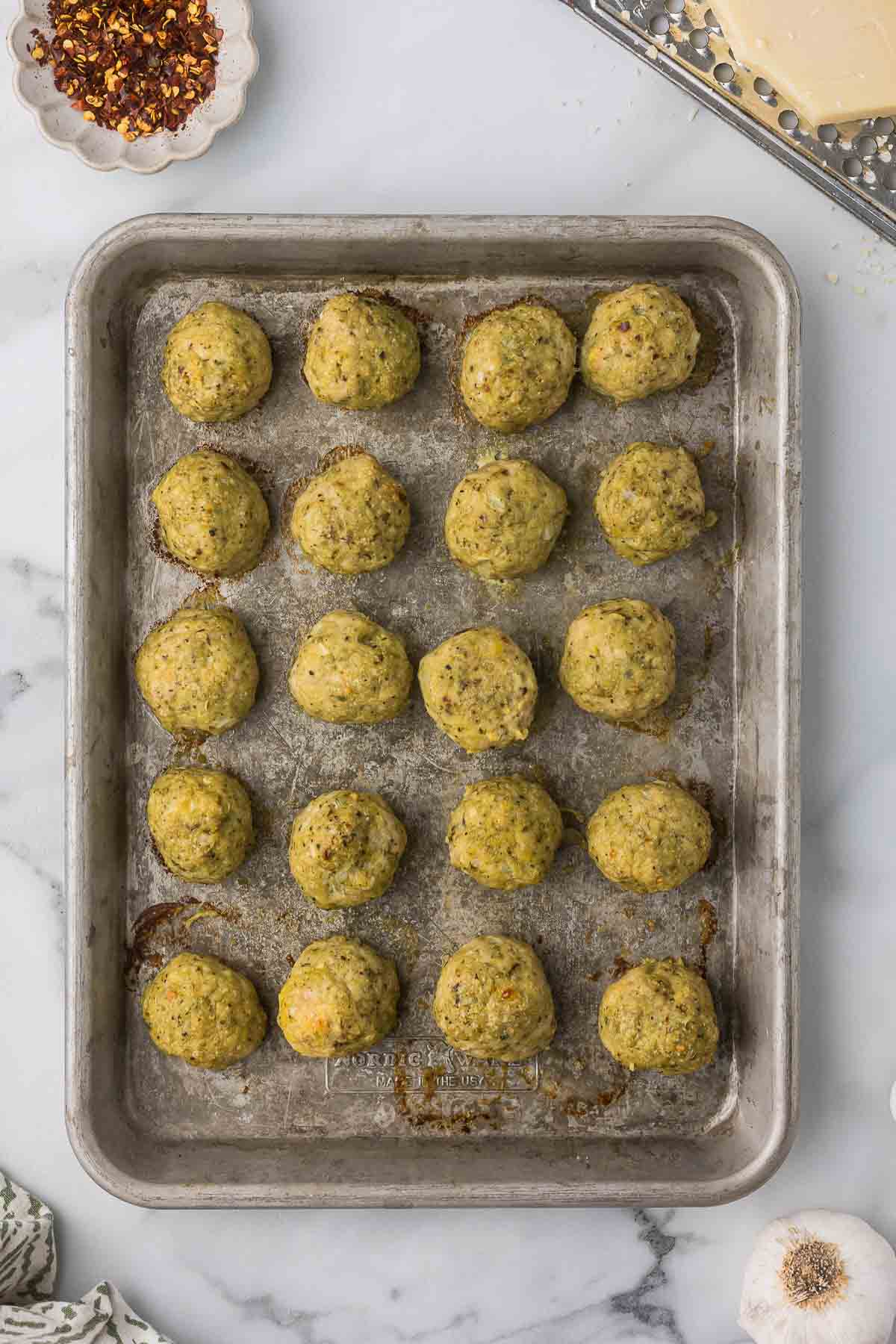 Baked chicken meatballs on a cookie sheet after they have come out of the oven.