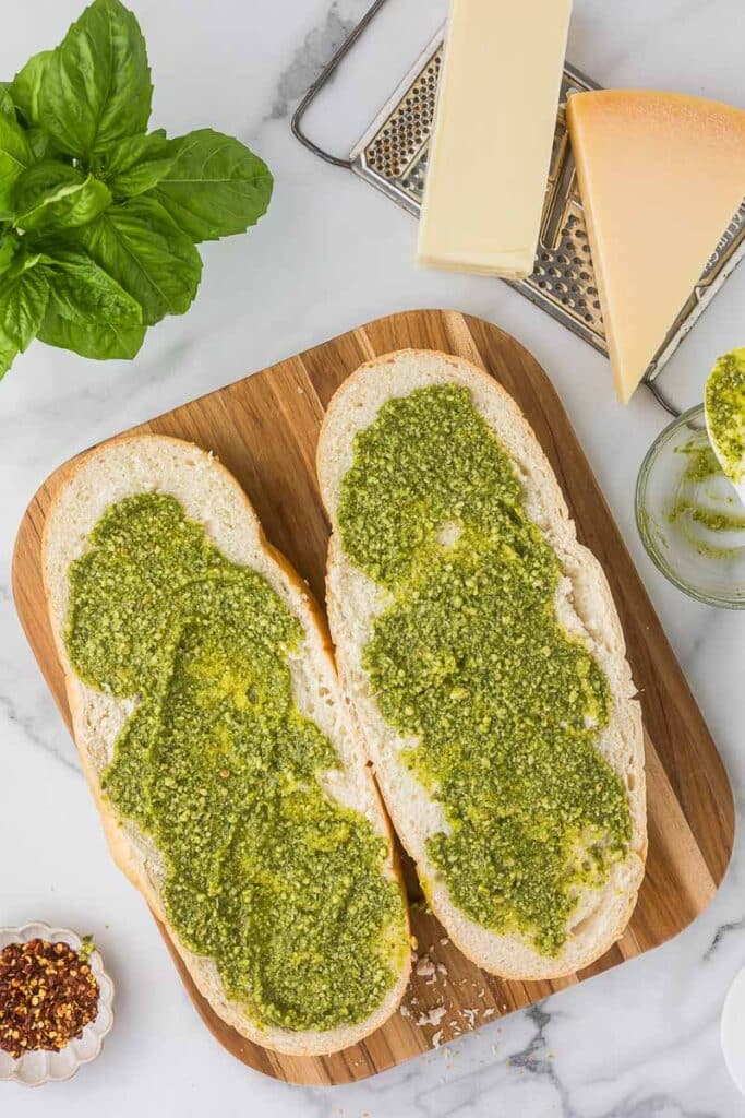 Italian bread cut length wise with garlic pesto spread over each half.