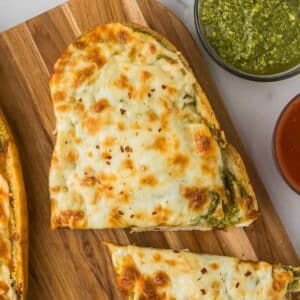 Pesto garlic bread on a cutting board.