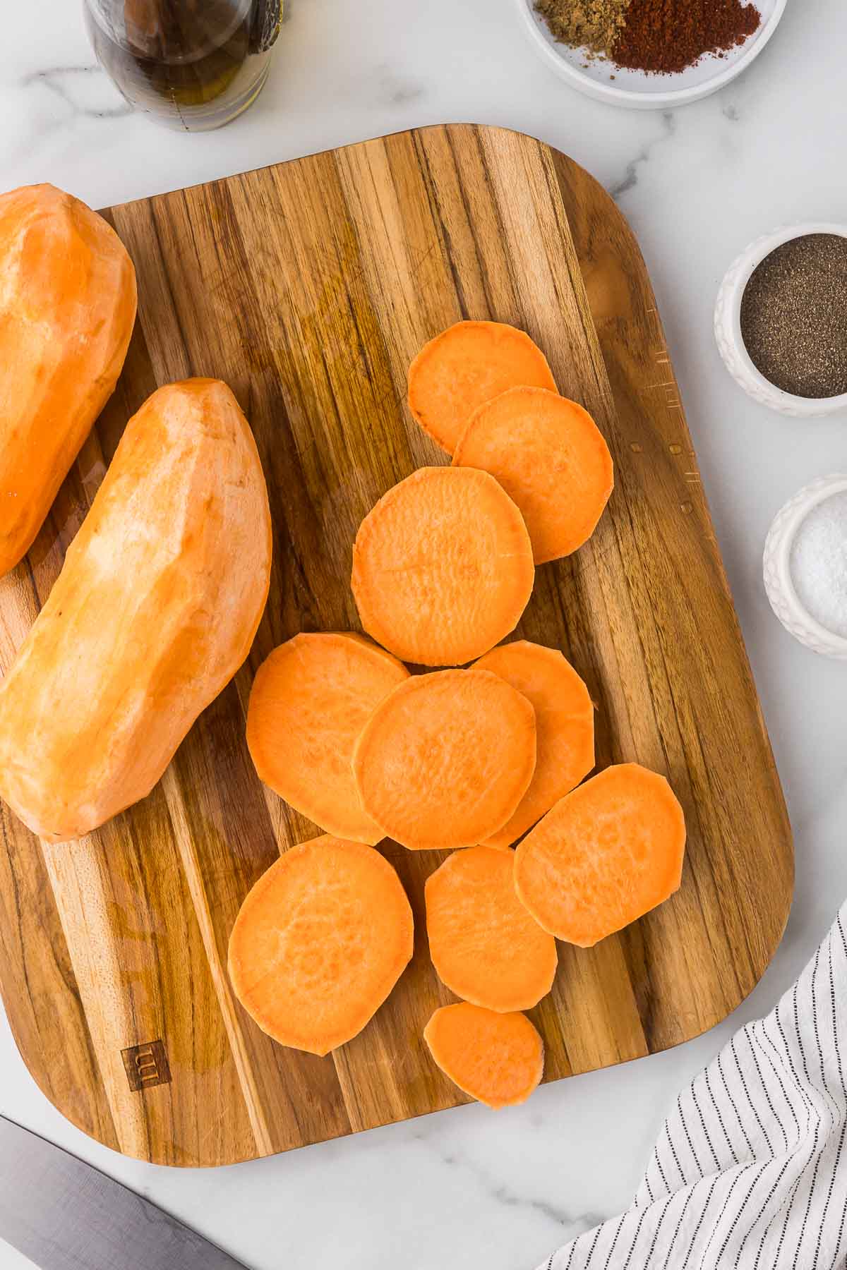 Sweet potatoes that have been sliced on a cutting board.