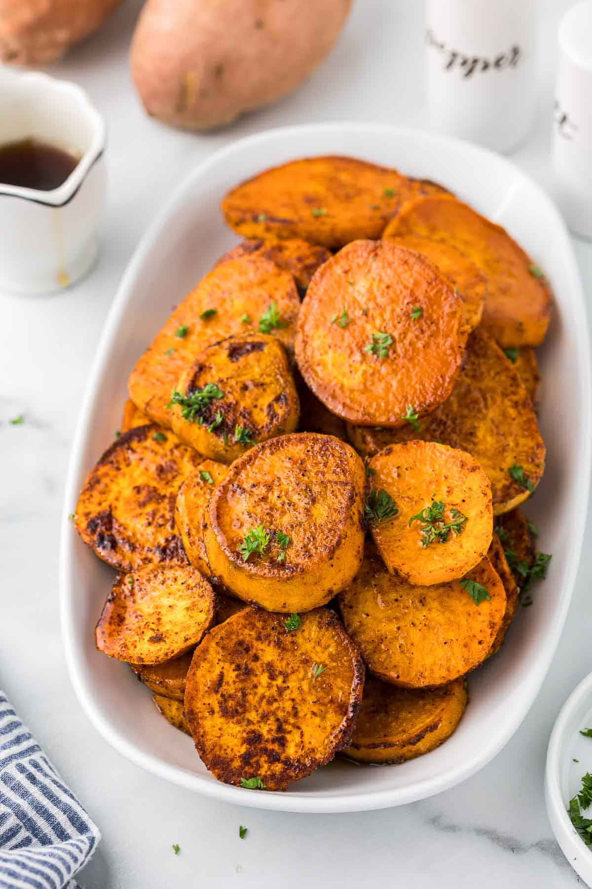 Roasted Sweet Potatoes with a drizzle of maple syrup on a white serving dish.