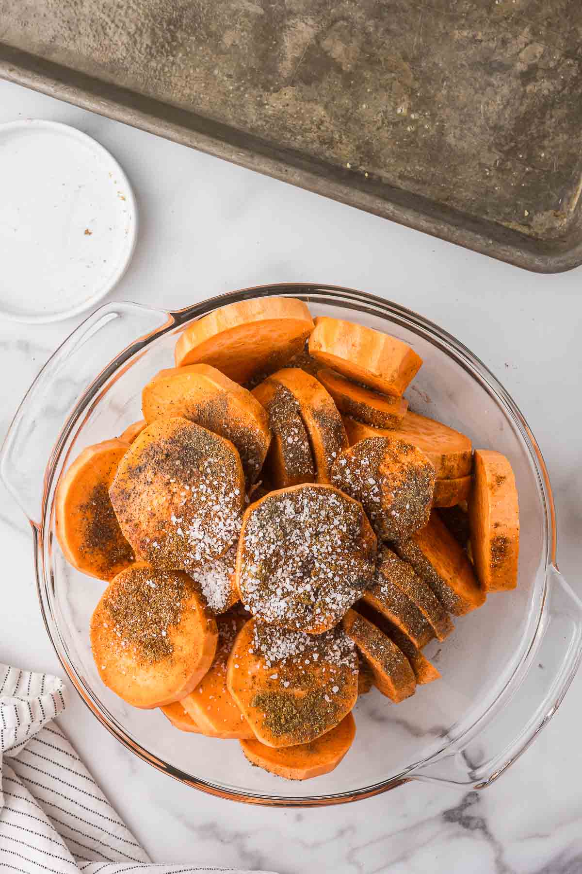 A bowl of sweet potato slices with olive oil and seasonings.