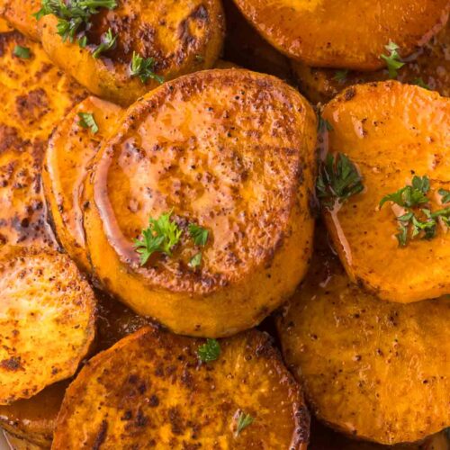 Roasted Sweet potatoes on a platter with parsley as garnish.