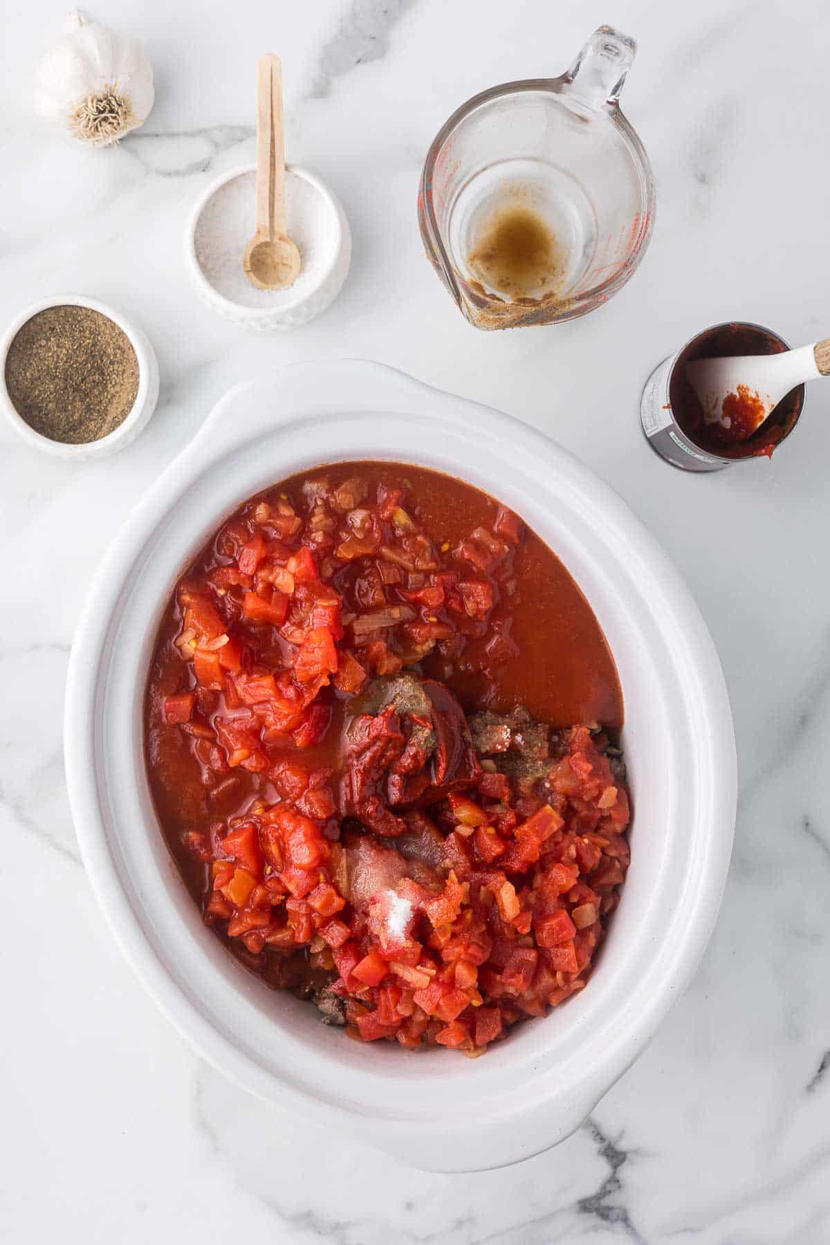 Chili ingredients in a white crock pot.