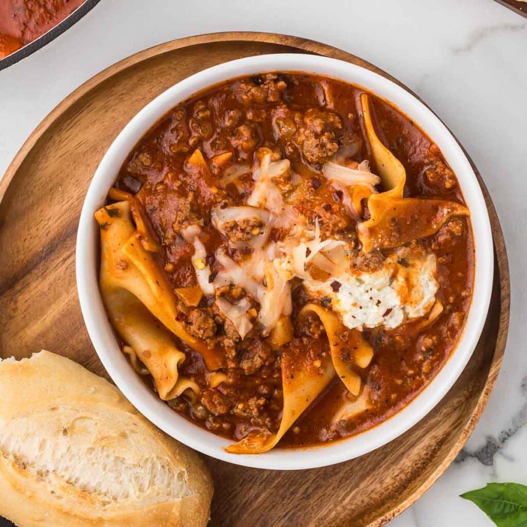 Lasagna Soup in a white bowl with a piece of bread.