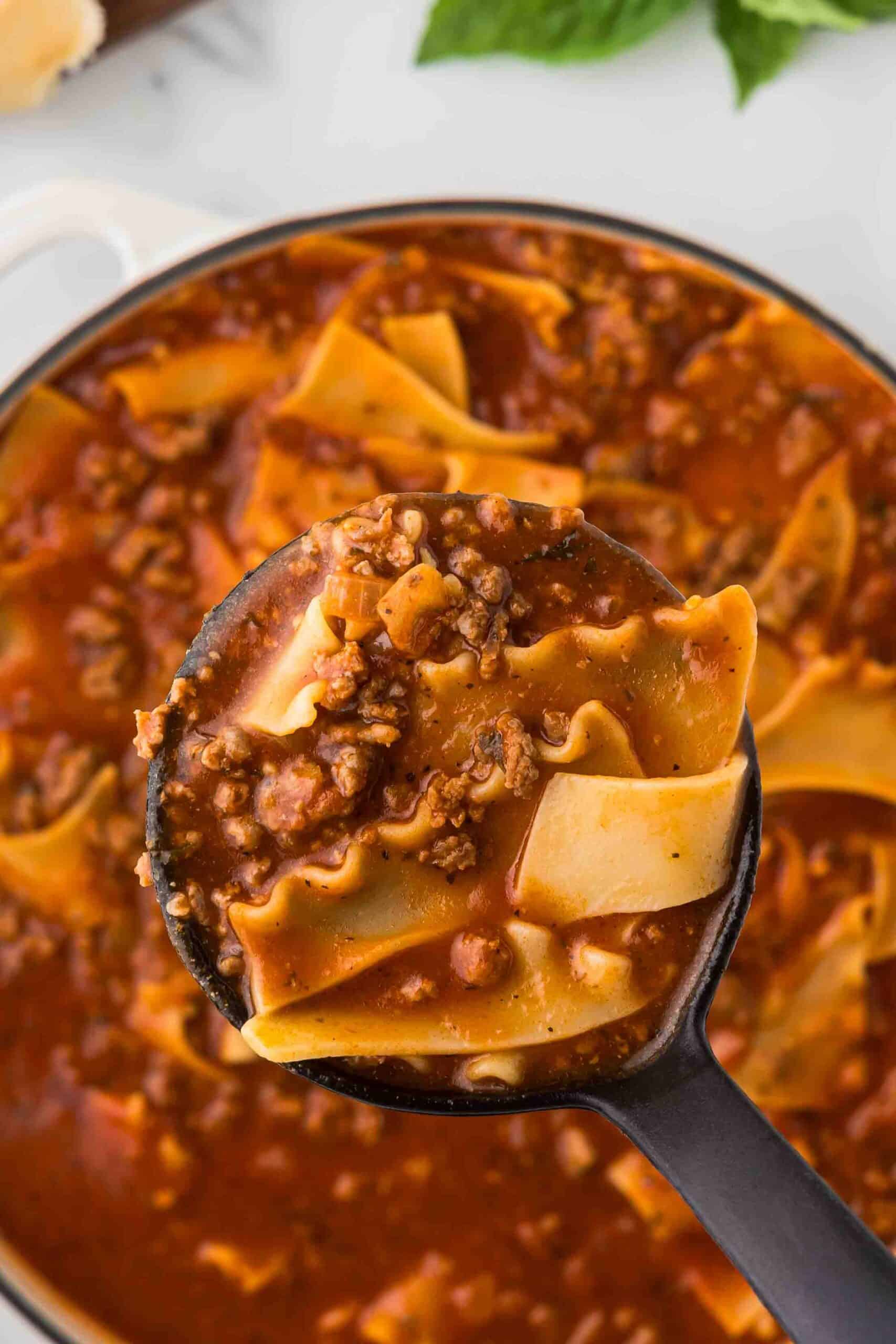 Close up of lasagna soup in a ladle.