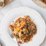 A white plate contains a serving of cabbage roll skillet dinner with rice, ground meat, and vegetables. A fork rests on the plate, and a skillet with more food is in the background. Text on the image reads "Quick Cabbage Roll Skillet Dinner: An Easy Dinner.