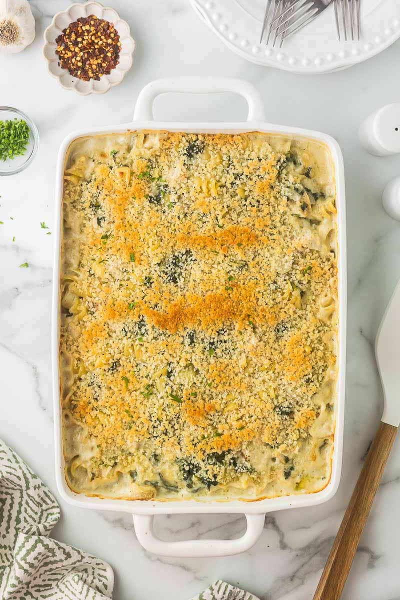 Spinach Artichoke Chicken Pasta in a white casserole dish after it has baked.