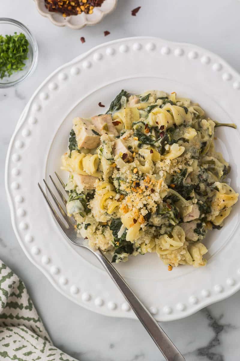 Spinach Artichoke Past on a white plate with a fork.