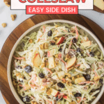 A bowl of apple cranberry coleslaw on a wooden platter. The coleslaw contains shredded cabbage, apple slices, cranberries, and walnuts. The image includes text: "Apple Cranberry Coleslaw - Easy Side Dish.