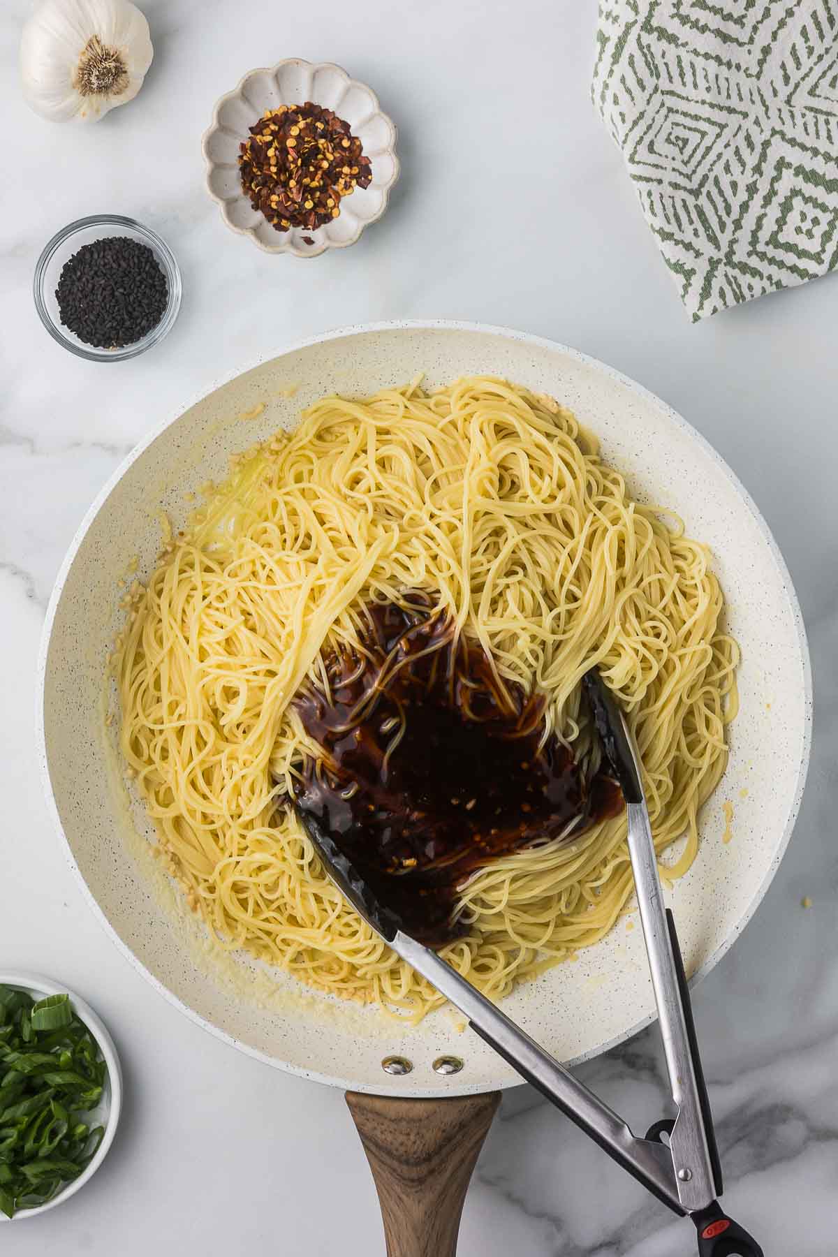 Butter noodles with garlic and teriyaki being mixed in with a spatula.