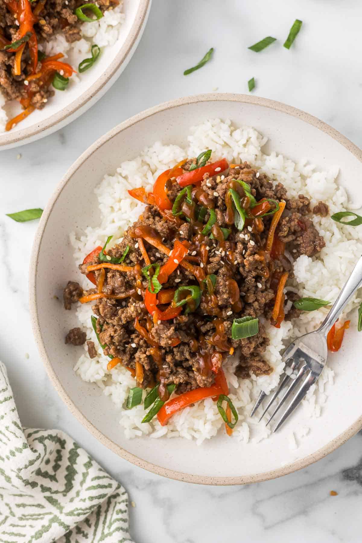 Ground Beef Teriyaki bowl with a fork in a white bowl with a linen.