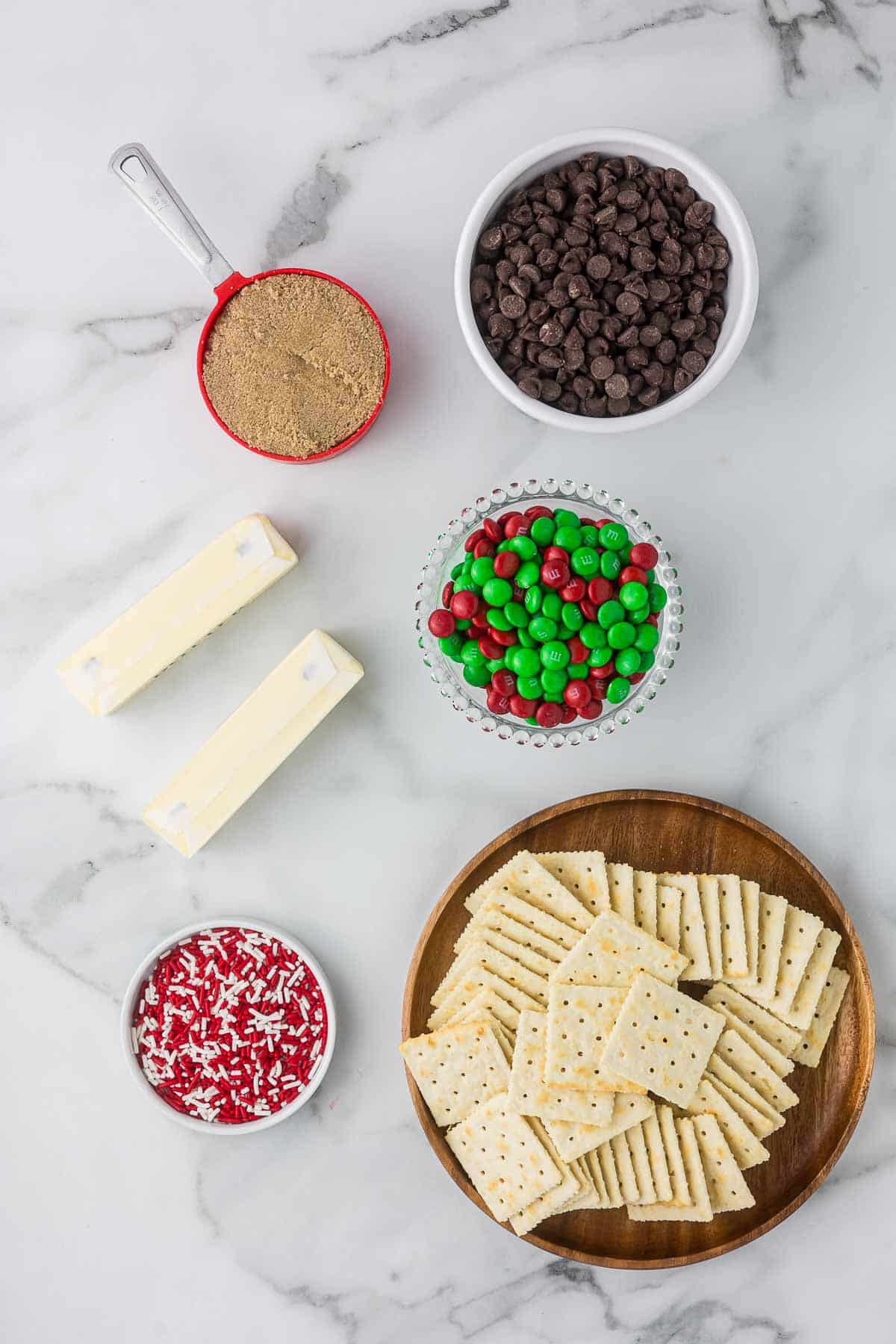 Ingredients to make Christmas Crack Recipe with brown sugar, butter, chocolate candies, chocolate chips and saltine crackers.