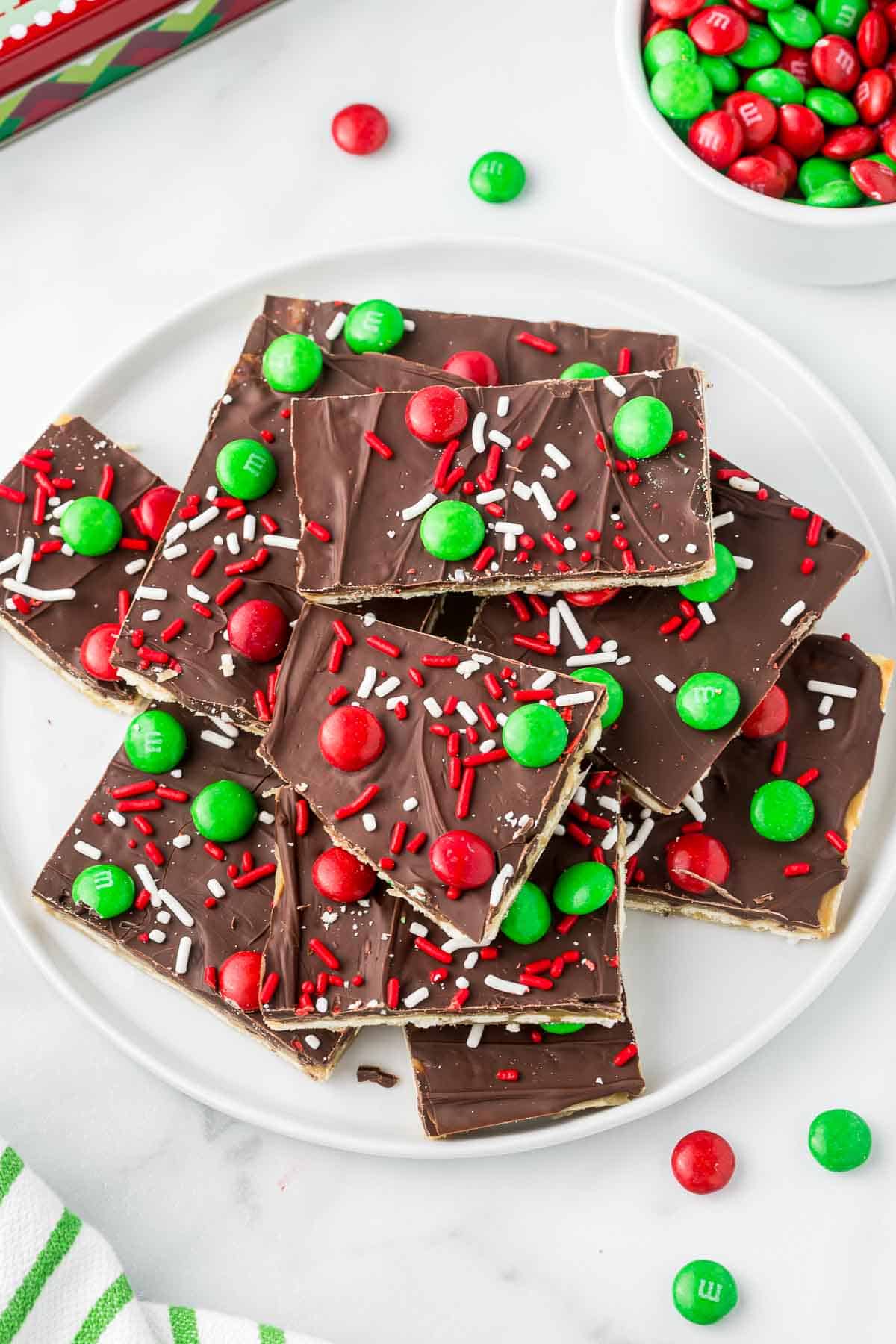 Saltine cracker toffee on a white plate with red and green m&m's.