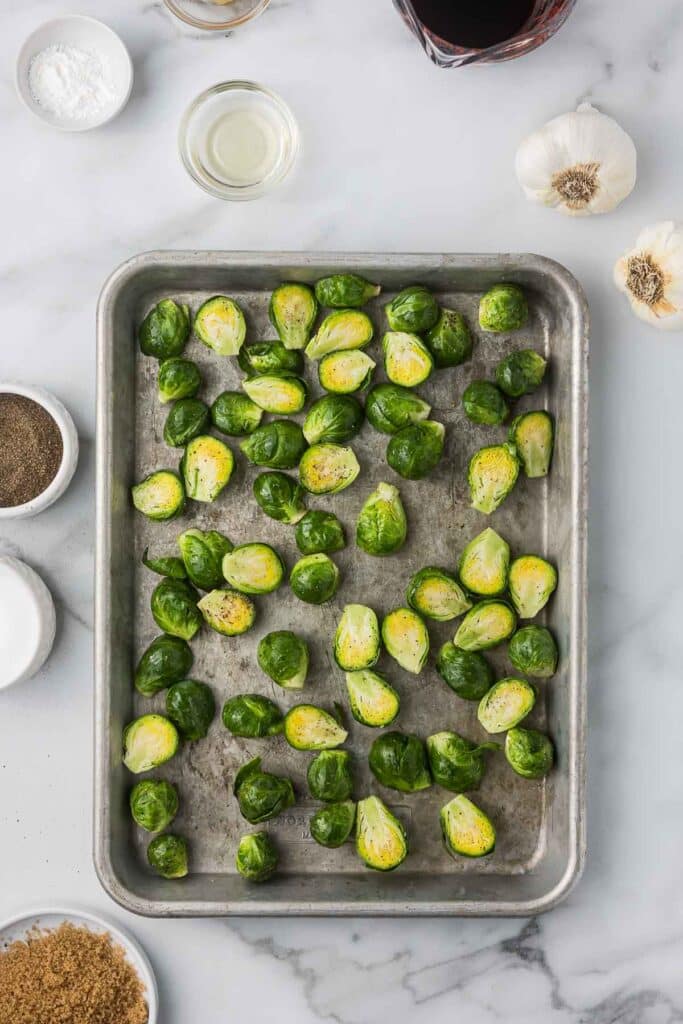 Brussels sprouts with olive oil, salt and pepper on a baking sheet before roasting.