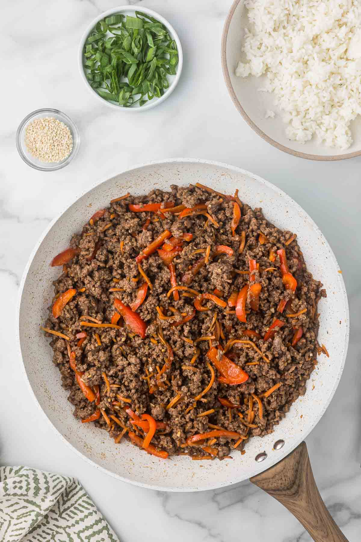 A skillet with the ground beef mixture for beef bowls.