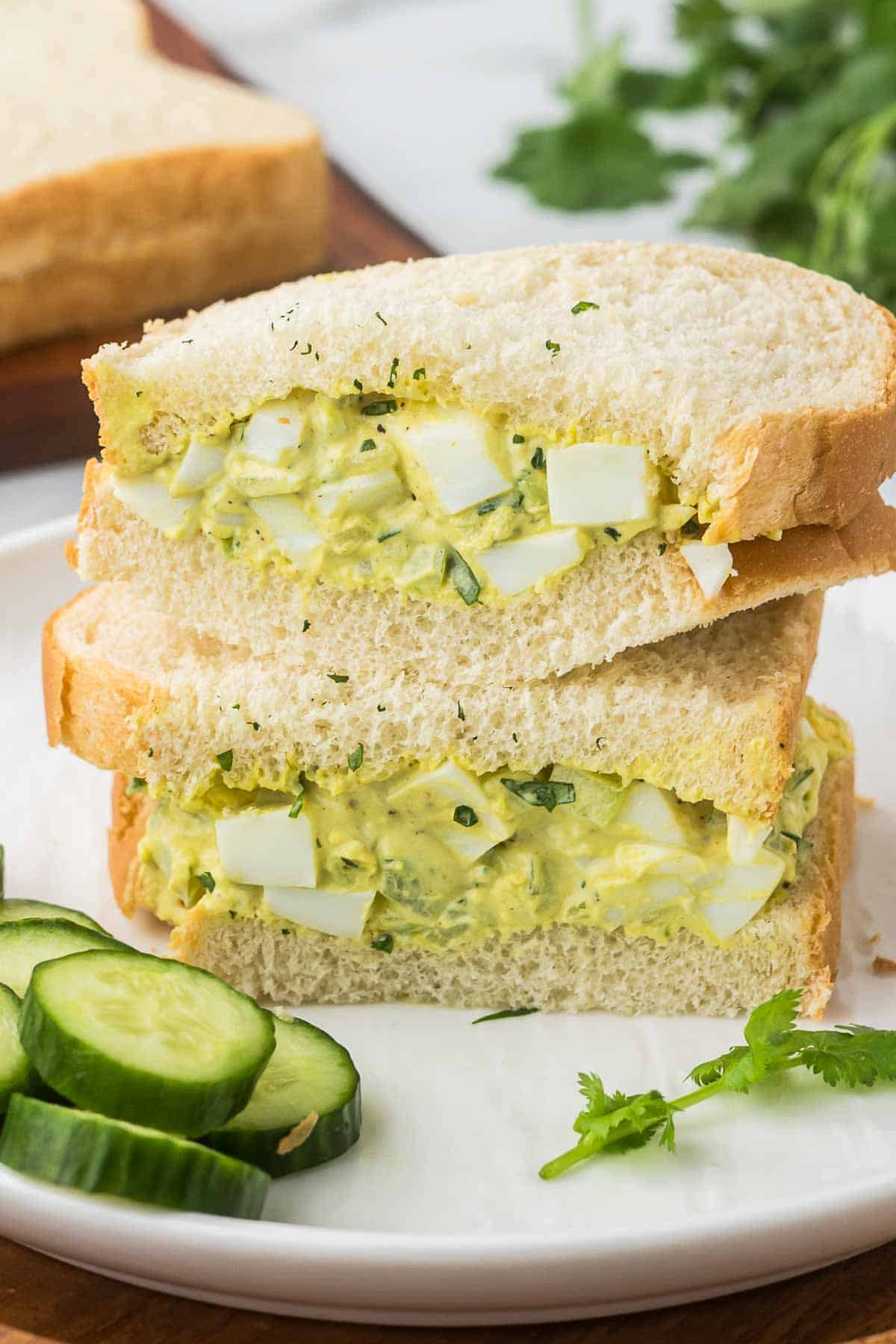 Curred egg salad sandwich cut into two stacked on top of each other. 