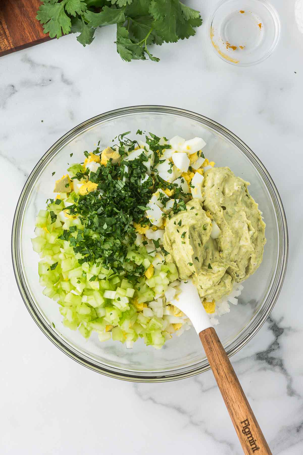 Ingredients in a glass bowl for curried egg salad.