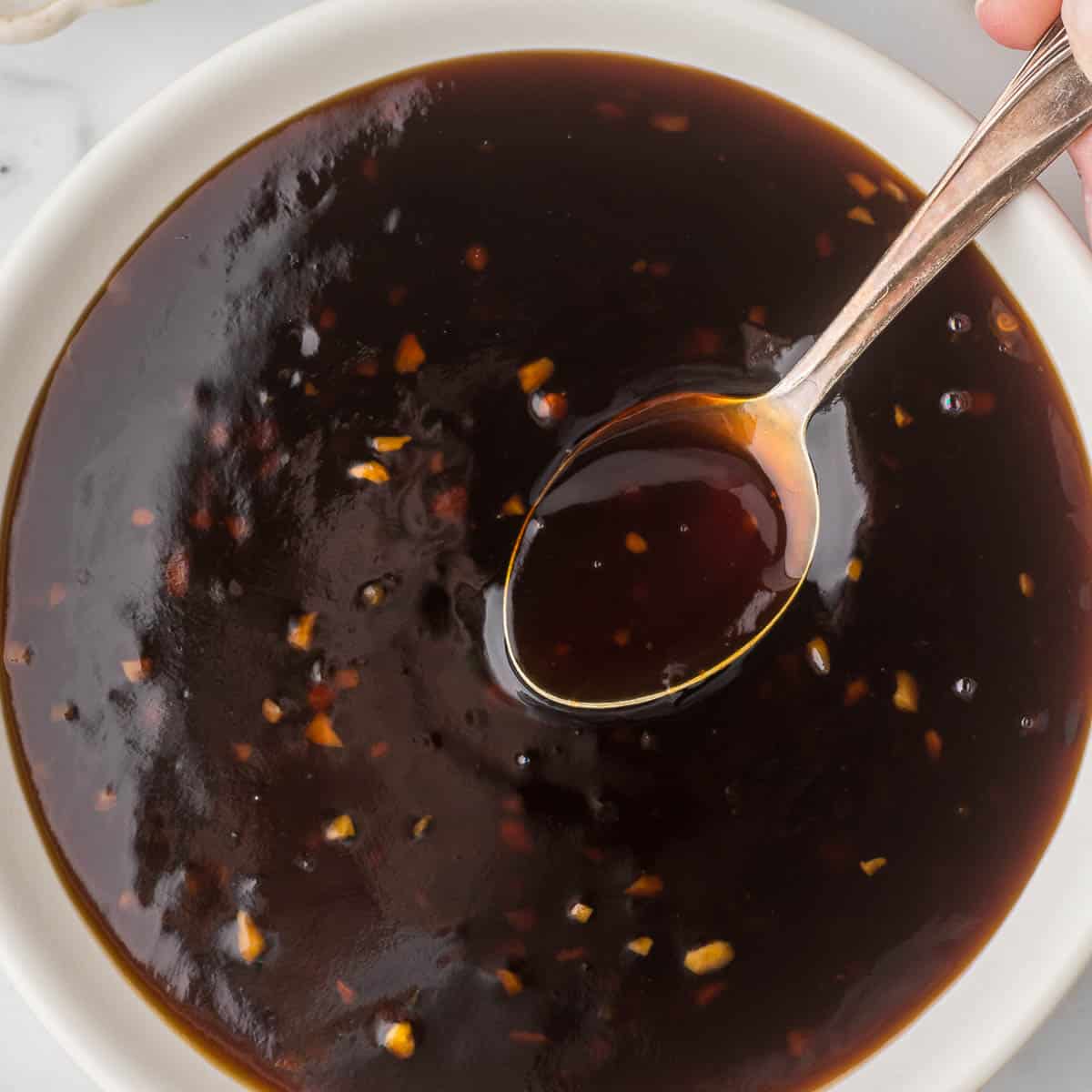 Teriyaki Sauce in a white bowl with a small serving spoon.