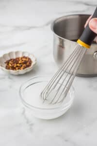 Corn starch in a small bowl with water and a whisk.