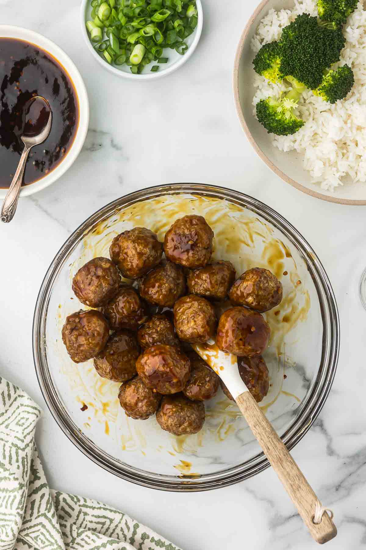 Meatballs being tossed in teriyaki sauce.