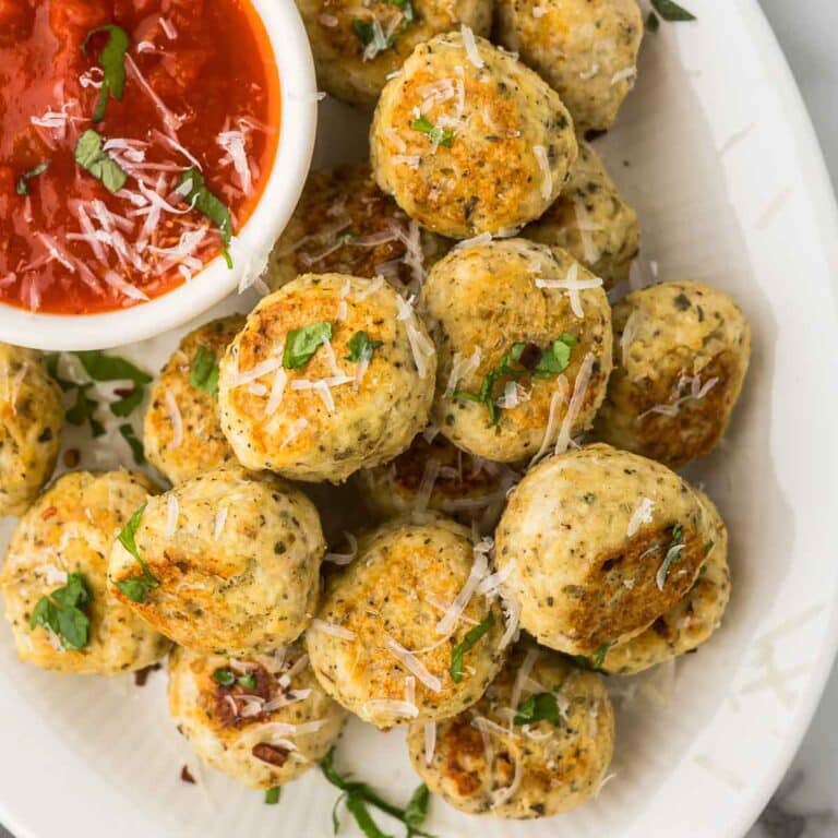 Italian Meatballs with Ricotta cheese served on a white plate with parsley and red sauce.