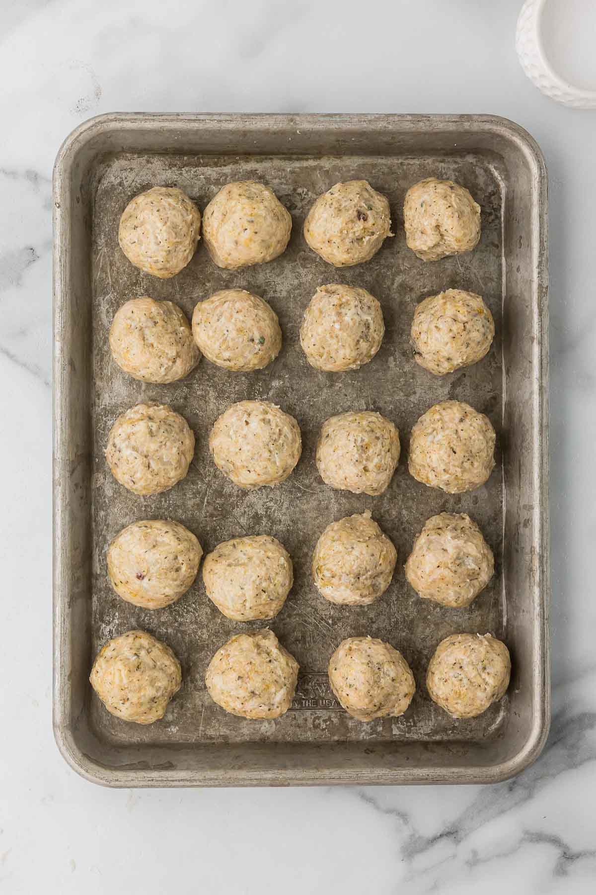 Chicken meatballs on a baking sheet before baking.