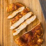 Chicken breast sliced on a cutting board.