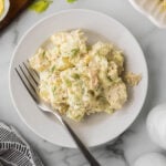 Tuna salad with potatoes on a white plate with a fork.